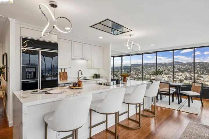 Kitchen with light stone counters, white cabinets, floor to ceiling windows, and dark wood-style flooring