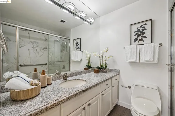 Bathroom featuring vanity and a marble finish shower