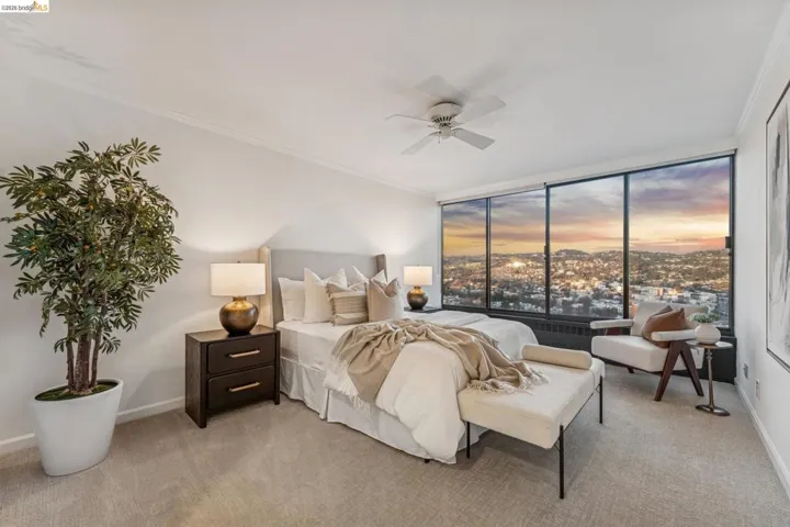 Bedroom with ornamental molding, light colored carpet, expansive windows, and a ceiling fan