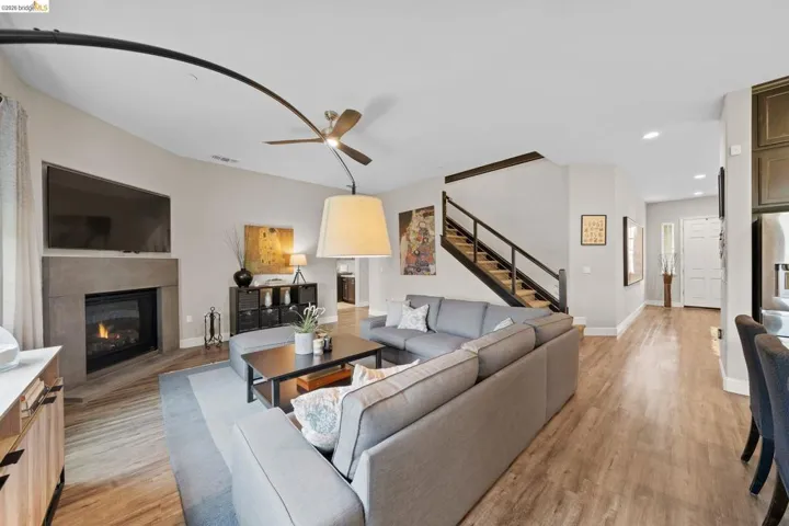 Living area featuring light wood-type flooring, a glass covered fireplace, recessed lighting, and a ceiling fan