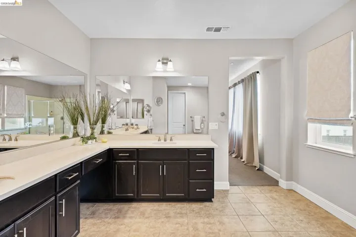 Full bath featuring plenty of natural light, double vanity, and light tile patterned floors