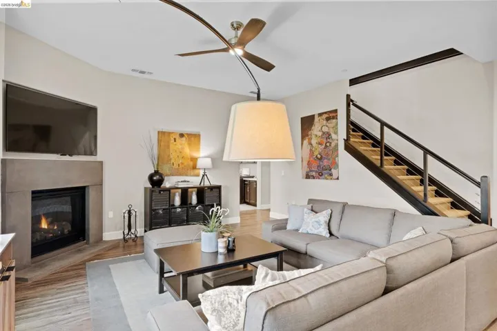 Living area featuring ceiling fan, light wood-style floors, and a glass covered fireplace
