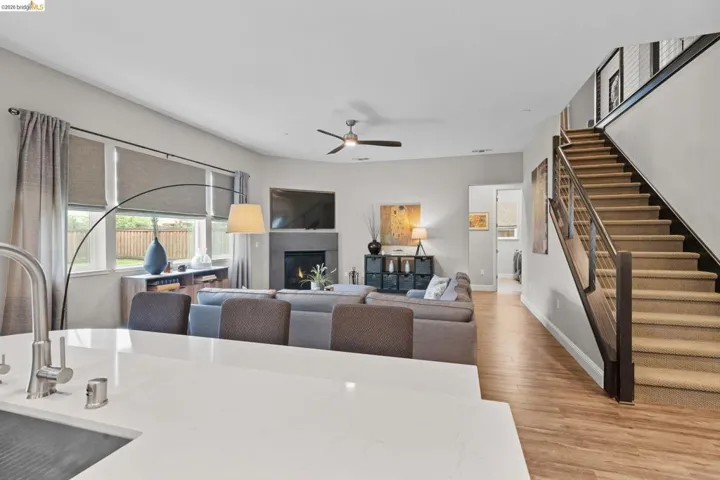 Dining area featuring a ceiling fan, light wood-style floors, and a warm lit fireplace