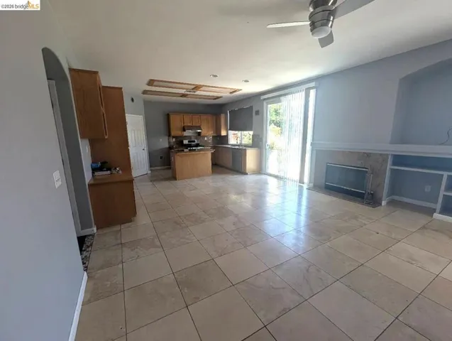 kitchen with a center island, a ceiling fan, wood finish cabinets, open floor plan, and stainless steel stove