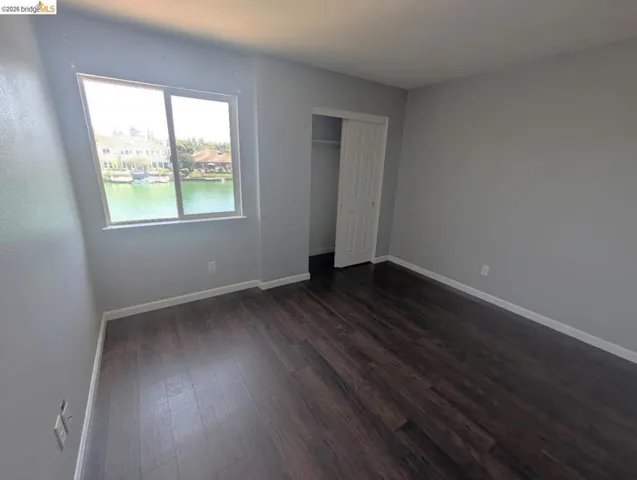unfurnished bedroom with a closet and dark wood-style flooring
