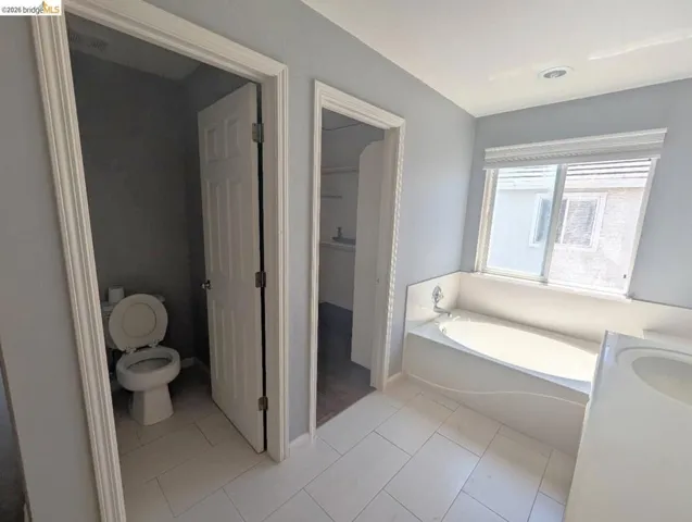 full bathroom with a bath, vanity, light tile patterned floors, and a closet