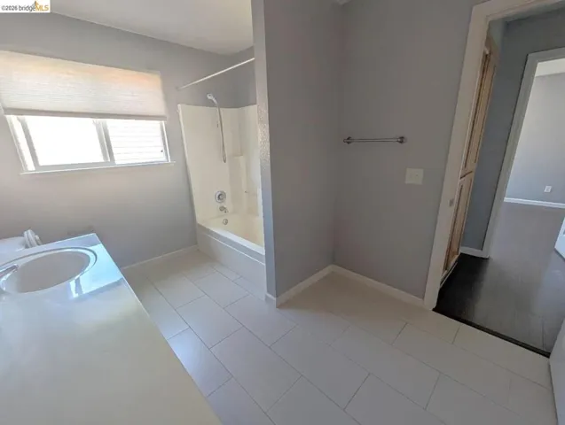 full bath with vanity, light tile patterned floors, and washtub / shower combination