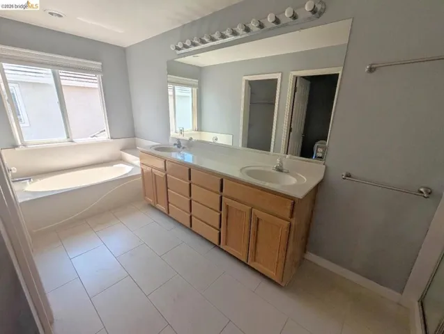 full bath featuring double vanity, a garden tub, and light tile patterned floors