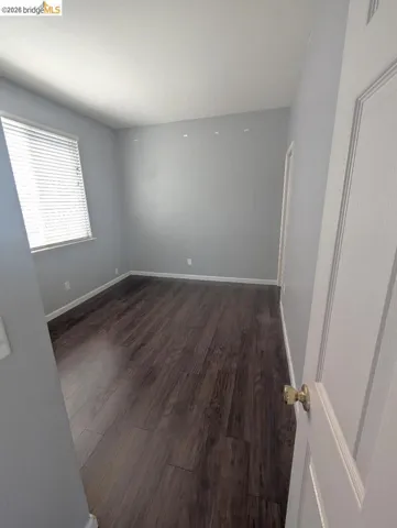 spare room with dark wood-style floors and baseboards