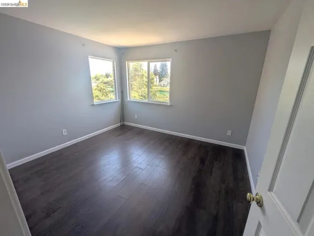 empty room with dark wood-style floors and baseboards