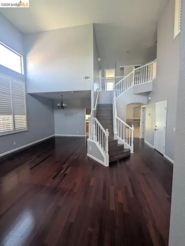 unfurnished living room featuring a high ceiling, dark wood finished floors, and a chandelier