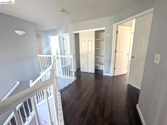hallway featuring an upstairs landing and dark wood-style flooring