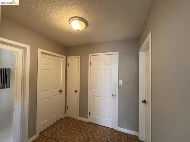 Hallway with a textured ceiling and dark tile patterned flooring