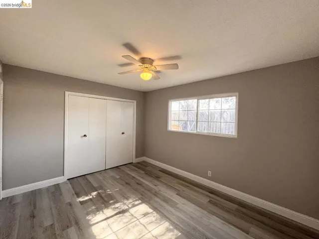 Unfurnished bedroom featuring light wood-type flooring, a closet, ceiling fan, and a textured ceiling