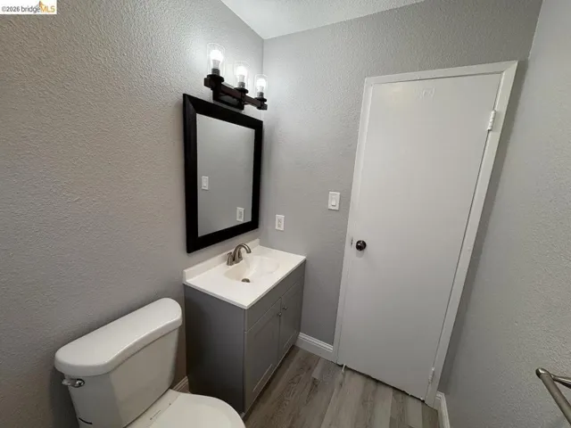 Bathroom featuring vanity, light wood-style flooring, and a textured wall