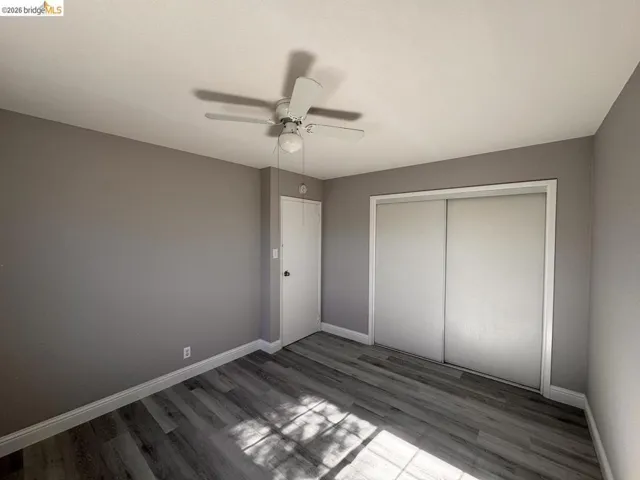 Unfurnished bedroom featuring wood finished floors, a closet, and a ceiling fan
