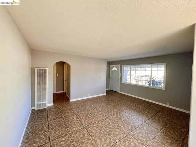 Unfurnished room with arched walkways, a heating unit, and a textured ceiling