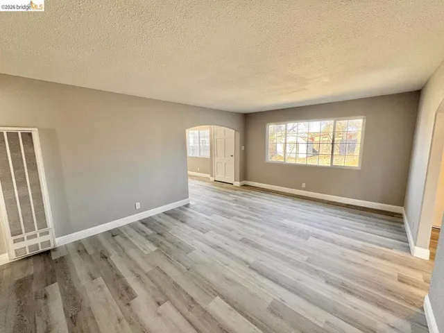Spare room with arched walkways, a heating unit, a textured ceiling, and light wood finished floors