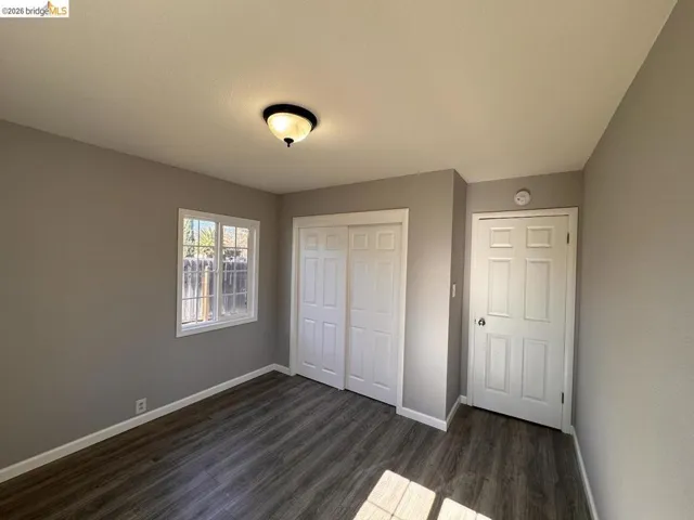 Unfurnished bedroom featuring dark wood finished floors and a closet