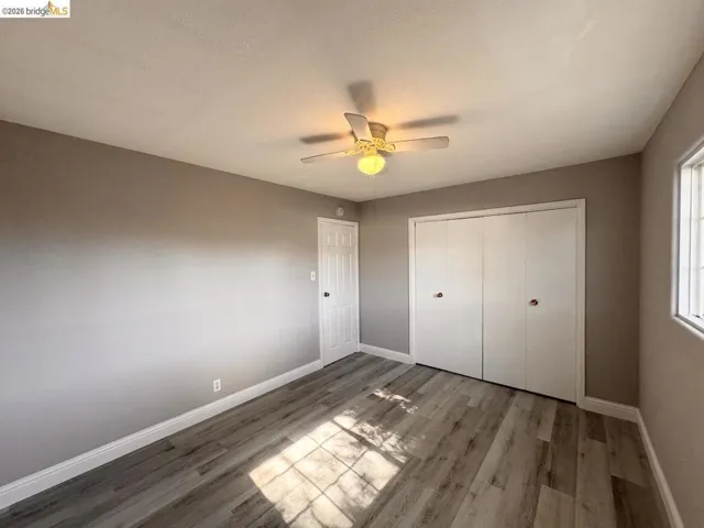 Unfurnished bedroom with light wood-style floors, a closet, and a ceiling fan