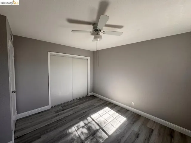 Unfurnished bedroom featuring a closet, dark wood finished floors, and ceiling fan