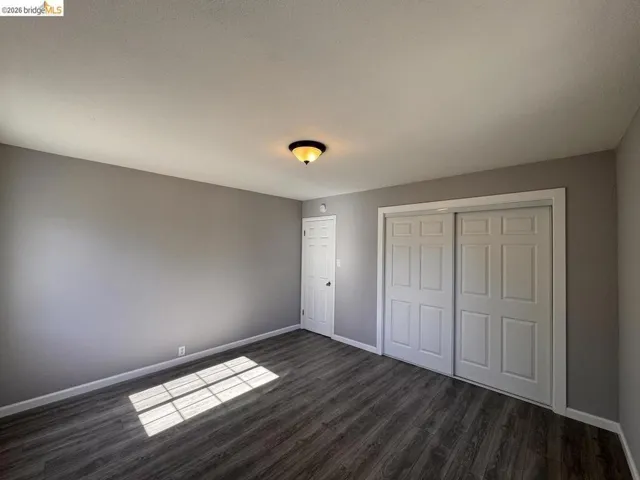 Unfurnished bedroom featuring a closet and dark wood-style floors