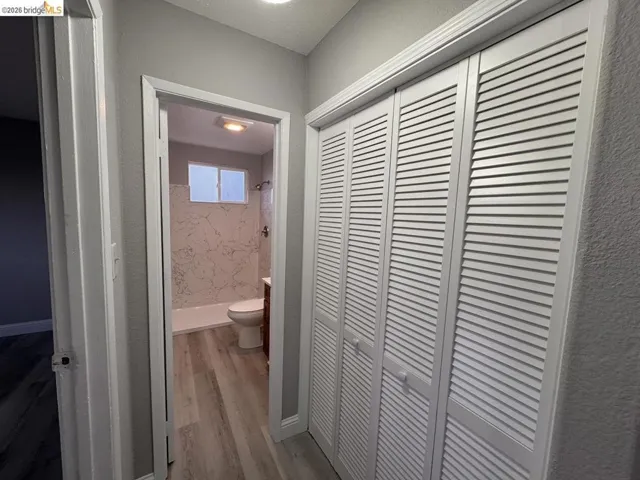 Hallway featuring light wood-type flooring and a textured wall