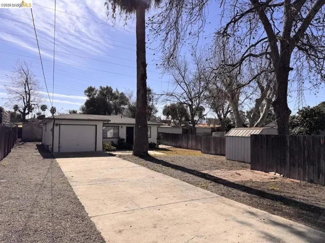 Fenced yard featuring concrete driveway, a garage, and a storage unit