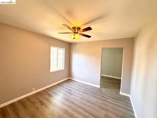 Spare room featuring light wood-style flooring, a textured ceiling, and a ceiling fan