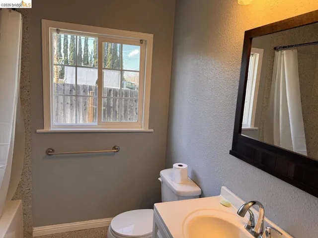Bathroom featuring vanity, a textured wall, and shower / bath combination with curtain