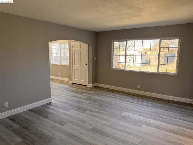 Foyer entrance with a textured ceiling, arched walkways, and light wood finished floors