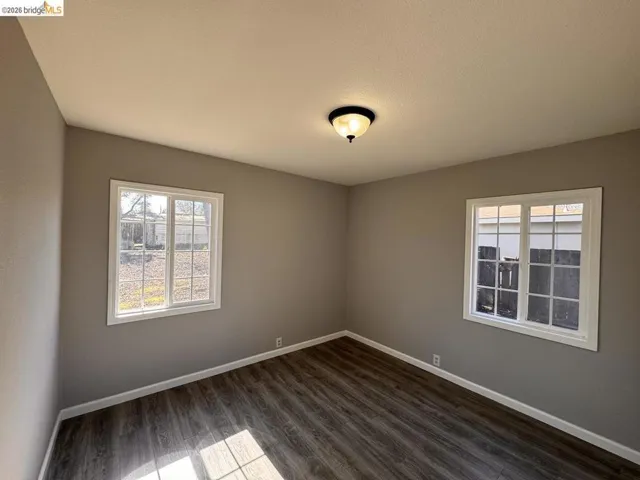 Unfurnished room featuring dark wood finished floors and plenty of natural light