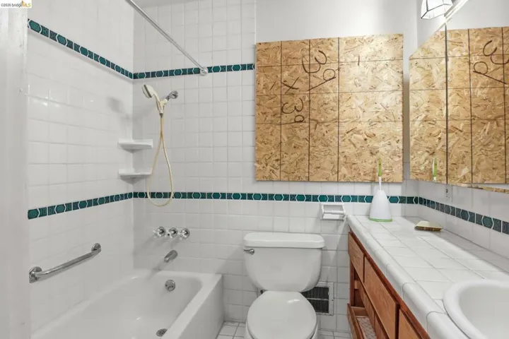 Bathroom with tile walls, tub / shower combination, and vanity