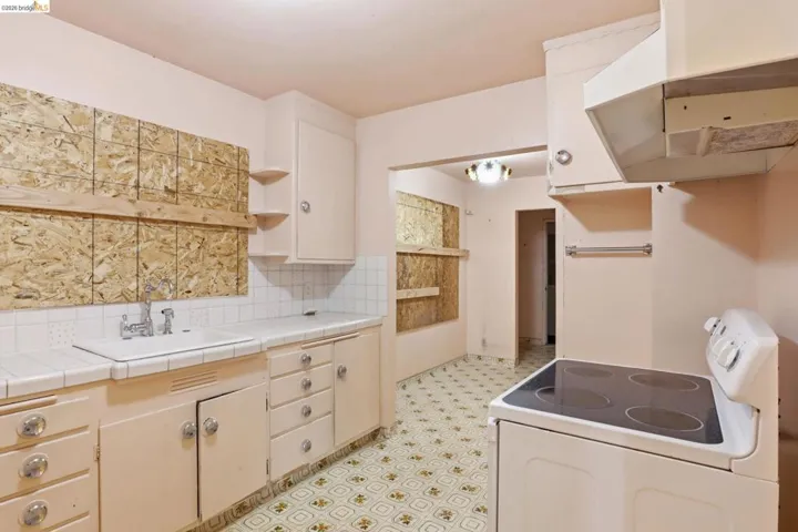 Kitchen featuring white electric range, light floors, tile countertops, and open shelves
