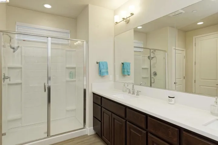 Full bath featuring a stall shower, double vanity, recessed lighting, and light wood finished floors