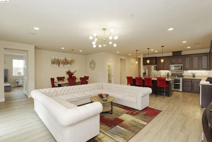 Living room with a chandelier, light wood-type flooring, and recessed lighting