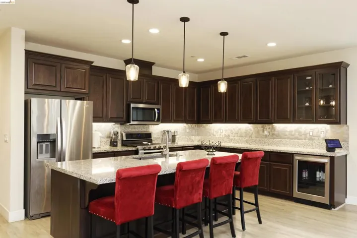 Kitchen featuring appliances with stainless steel finishes, backsplash, dark brown cabinetry, beverage cooler, and recessed lighting