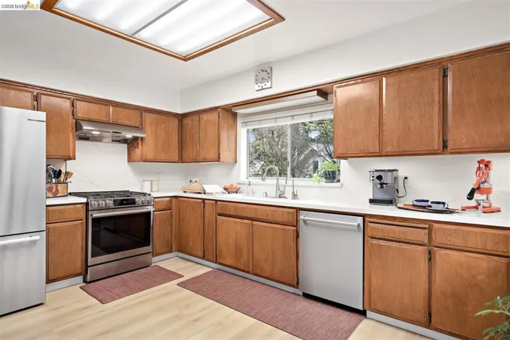 Kitchen featuring stainless steel appliances, light countertops, wood finish cabinetry, and light wood-type flooring
