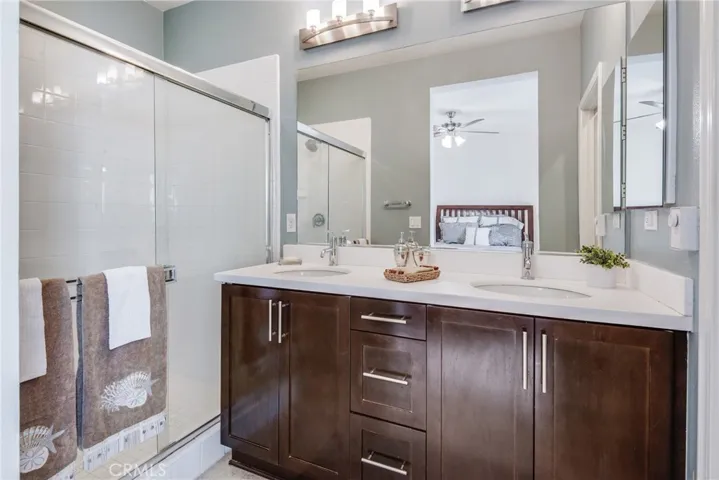 The primary bathroom with walk in shower, rich dark vanity with 2 sinks, beautiful lighting and more.