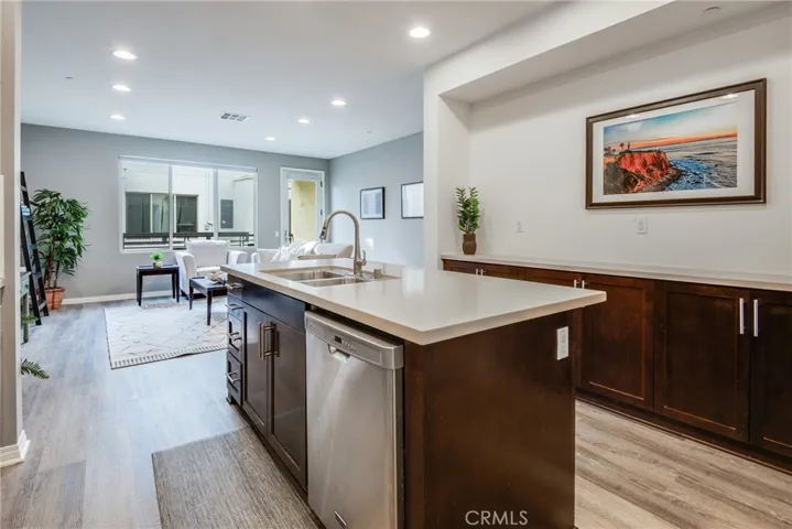 Beautiful and open concept kitchen with rich cabinetry pantry, quartz countertops, stainless appliances, wide plank flooring, counterop seating centered around the island