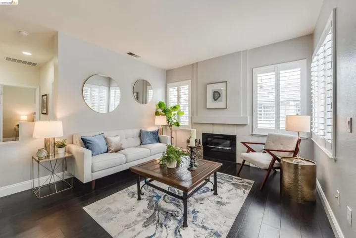 Living room with a tile fireplace and dark wood-style flooring