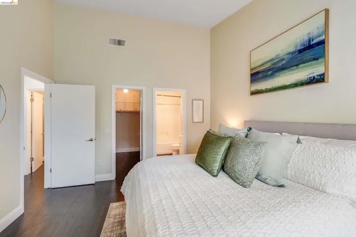 Bedroom featuring a spacious closet, dark wood finished floors, ensuite bath, and a high ceiling