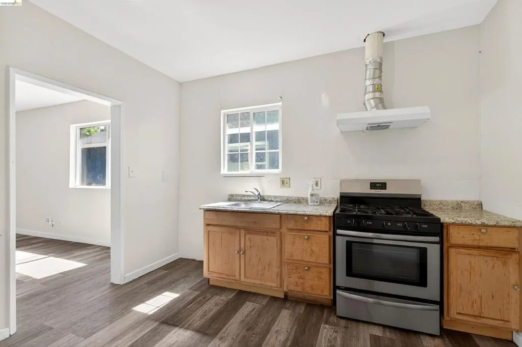 Kitchen space featuring wood-finish flooring, light wood cabinetry, and a stone-look countertop