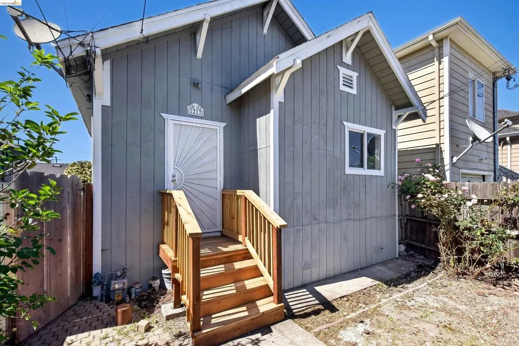 Gray vertical board siding with white trim accents and a detailed storm door