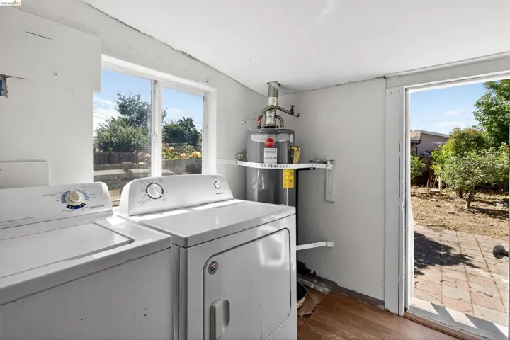 Laundry area featuring a window, wood-finish flooring, and direct exterior access