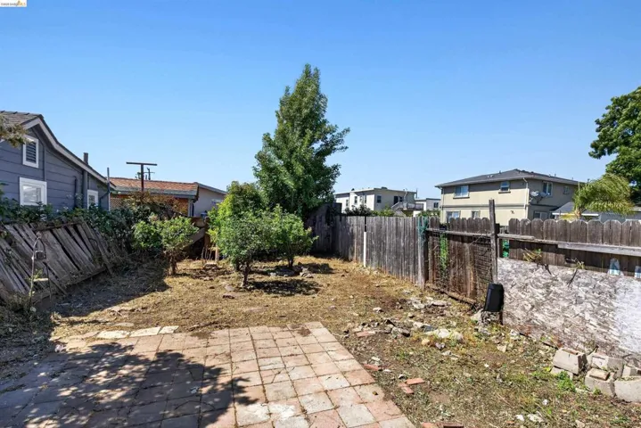 Spacious outdoor area featuring a brick patio, mature trees, and perimeter fencing