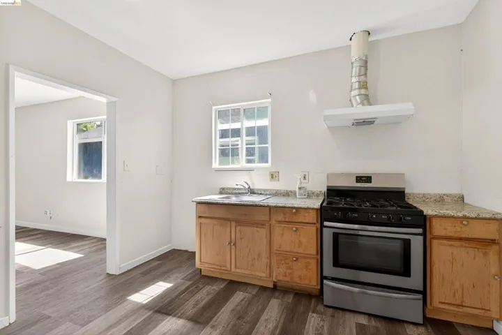 Kitchen space featuring wood-finish flooring, light wood cabinetry, and a stone-look countertop
