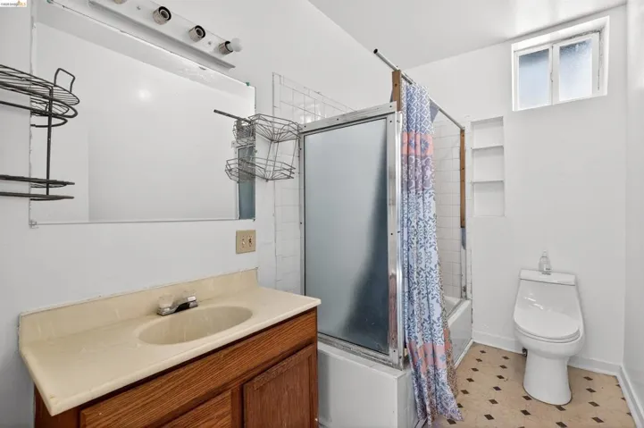 Full bathroom featuring a wood-finish vanity with an integrated sink, a built-in recessed shelf unit, and a window for natural light