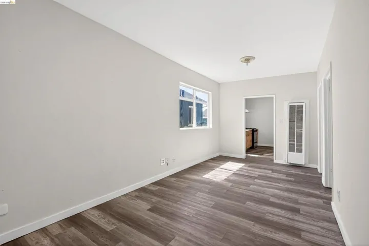 Spacious room featuring wood-finish flooring, white baseboards, and neutral wall tones