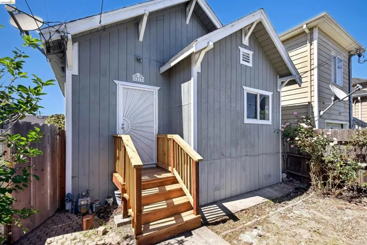 Gray vertical board siding with white trim accents and a detailed storm door